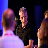 Dr. Andreas Böhm, Leiter für Quantentechnologie, Bayern Innovativ GmbH spricht im Rahmen einer Diskussionsrunde mit den Teilnehmenden. Im Vordergrund sind Zuhörende zu sehen.