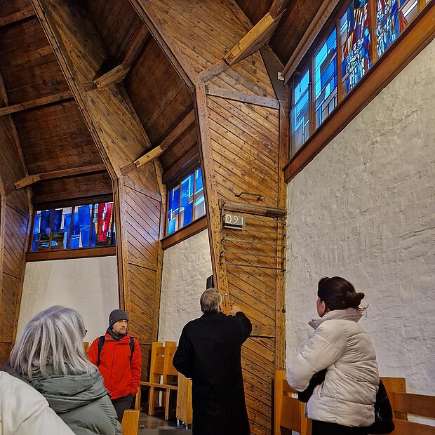 Herr erklärt im Innenraum einer Kirche eine Gruppe architektonische Besonderheiten. 