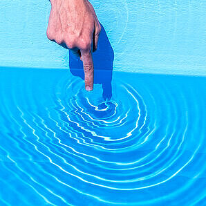 Finger der Wasser berührt