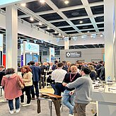 Auf dem Bild sind viele Personen zu sehen, welche sich auf einer Messe befinden.