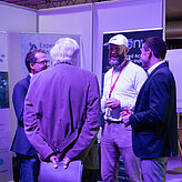 Das Bild zeigt vier Männer die sich vor einem Ausstellungsstand unterhalten