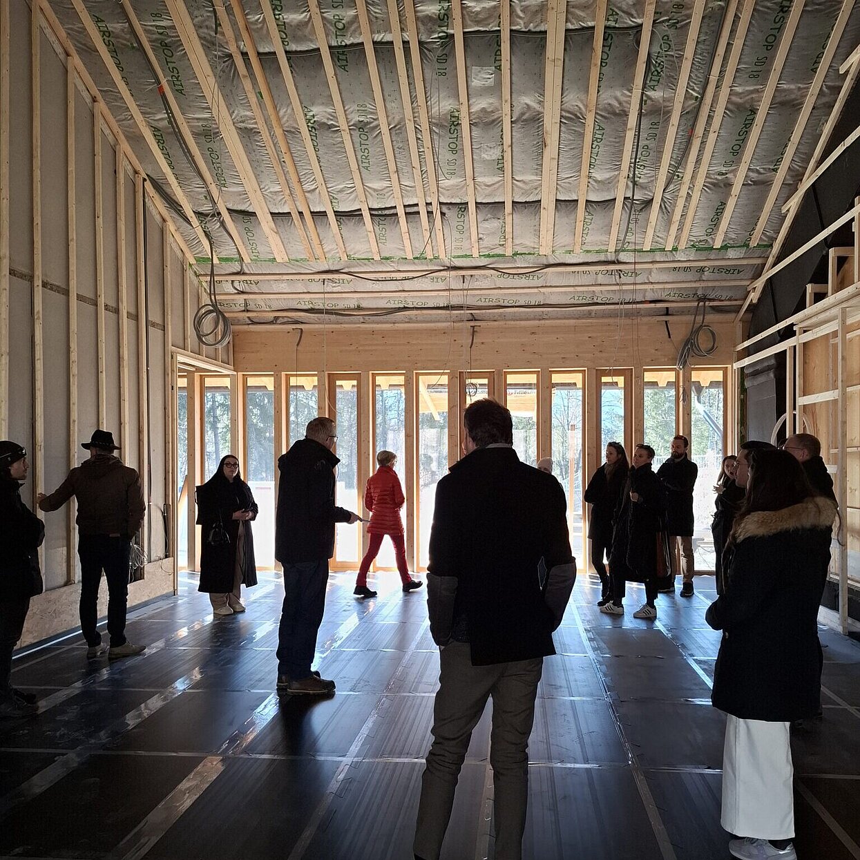 Mehrere Menschen in einem Holzbaukonstrukt-Gebäude. 