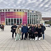 Auf dem Bild ist eine Gruppe von Personen zu sehen, welche sich für ein Gruppenfoto vor einem großen Gebäude zusammengestellt haben.