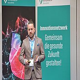 Eine Person steht vor zwei Bannern.