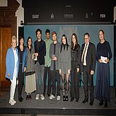 Tobias Gotthardt, Staatssekretär im Bayerischen Staatsministerium für Wirtschaft, Landesentwicklung und Energie, und Petra Lorenz, Geschäftsführerin des CommClubs Bayern e.V., stehen gemeinsam mit bayerischen Gewinnern und Gewinnerinnen des diesjährigen Cannes Lions auf einer Bühne.