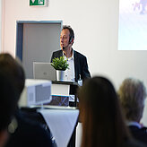 Ein Referierender spricht auf der Bühne