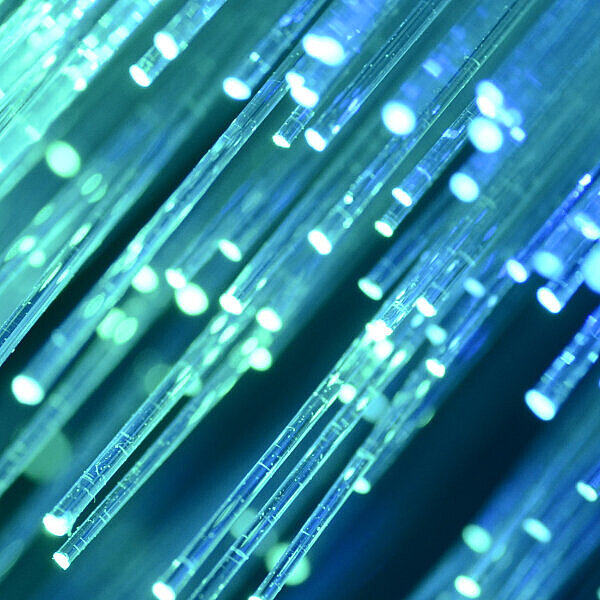 Leuchtende Glasfaserkabel in Grün und Blau als Symbol für digitale Vernetzung
