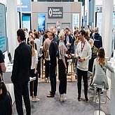 Menschenmenge auf einer Messe vor einem Stand mit dem Schriftzug 'bayern innovativ Innovation leben'