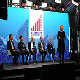 Dr. Parsons moderation a discussion on the stage while speakers sit on the chairs behind her