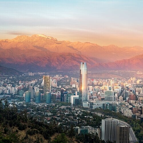 Stadtansicht von Santiago de Chile im warmen Abendlicht, mit Hochhäusern und den Anden im Hintergrund.