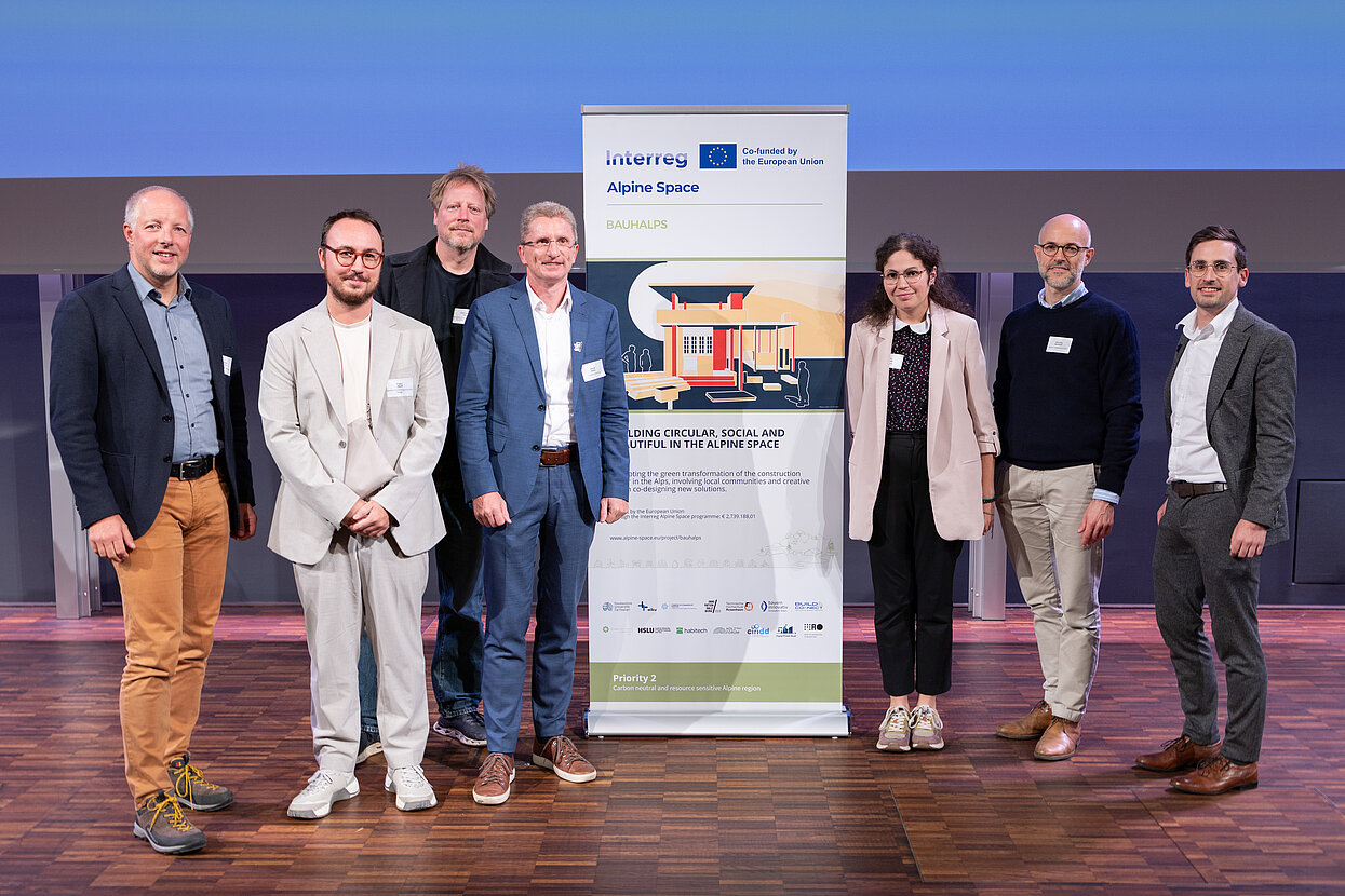 Gruppenbild vor einem Roll-up des Projektes Bauhalps. 