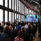 The plenum from the back watching the presentation with a view of the cloudy skyline of Munich