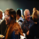 Guests of the Summit networking with a smile. Food and wine in their hands