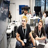 Menschen sitzen an einem Tisch und arbeiten