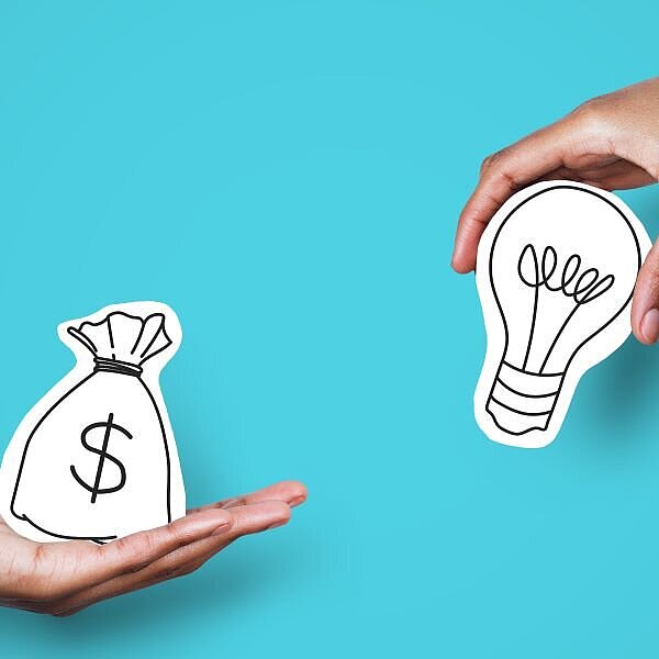 EIne Hand hält einen symboloschen Geldsack mit einem Dollersymbol, die andere Hand hält eine Glühbirne, welche eine Idee symbolisiert
