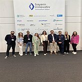 Auf dem Bild ist eine Gruppe von Personen zu sehen, welche vor einer Pressewand mit verschiedenen Logos, posieren.