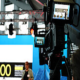 A view of the camera facing the stage in the background where a presentation takes place