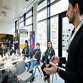 Menschen sitzen an einem Tisch und führen eine lebhafte Diskussion.