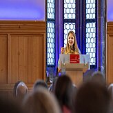 Eine Frau hält eine Rede vor einer Menschenmenge und spricht mit Leidenschaft zu ihrem Publikum