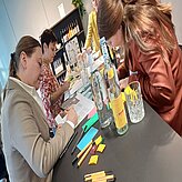 Menschen sitzen an einem Tisch und arbeiten, es liegen Post it's auf dem Tisch