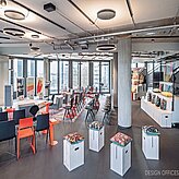 heller Veranstaltungsraum mit weißen Hockern und schwarzen Stühlen