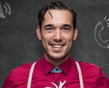Auf dem Bild ist ein Herr mit rotem Hemd zu sehen und dunklen Haaren
