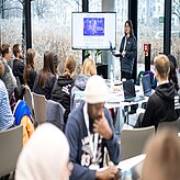 Menschen sitzen an Tischen und arbeiten zusammen