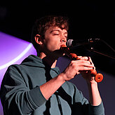 Das Bild zeigt einen jungen Mann mit einer Flöte