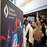 Menschen stehen um Stehtische und unterhalten sich 