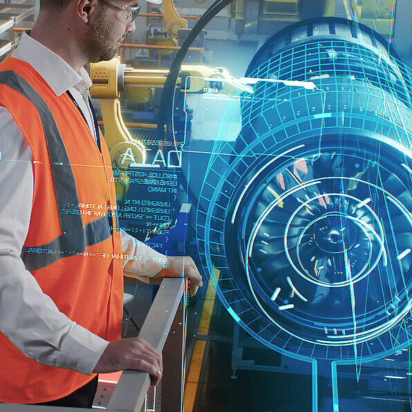 Arbeiter in einer modernen Fertigungsumgebung mit holographischer Anzeige eines Maschinenbauteils, umgeben von Produktionsanlagen und Robotern.