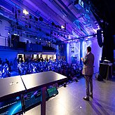 Tobias Gotthardt, Staatssekretär, Bayerisches Staatsministerium für Wirtschaft, Landes-entwicklung und Energie spricht auf einer Bühne vor einem Publikum.