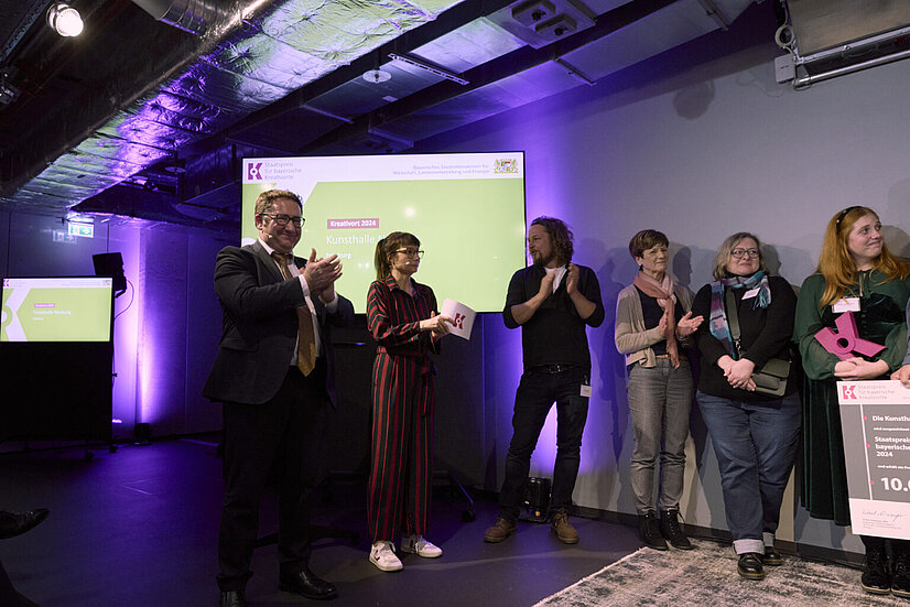 Staatssekretär Tobias Gotthardt, Bayerisches Staatsministerium für Wirtschaft, Landesentwicklung und Energie, Nina Sonnenberg, Moderation, und Preisträger Kunsthalle Neuburg