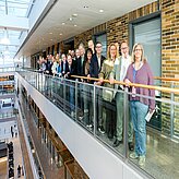 Teilnehmergruppe steht auf einer Galerie im Inneren eines modernen Gebäudes mit Glasfassade. Das Bild wurde bei der Delegationsreise in Kanada aufgenommen.