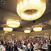 Das Bild zeigt einen großen, elegant beleuchteten Konferenzsaal mit zahlreichen Teilnehmenden, die konzentriert dem Programm des Batteriekongresses 2025 folgen.