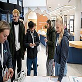 Frauen und Männer stehen an einem Check in Schalter in einem Eingangsbrereich