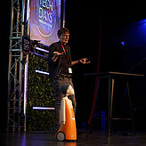 Das Bild zeigt einen Mann und einen Roboter auf einer Bühne. 