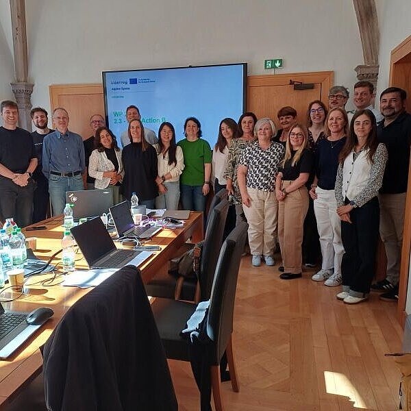 Eine Gruppe von Menschen steht in einem Besprechungsraum für ein Gruppenfoto zusammen.