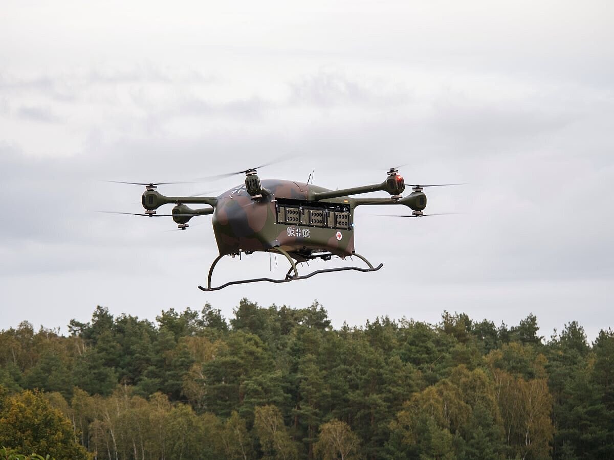 Eine kleine Militärdrohne fliegt über einen dichten Wald.