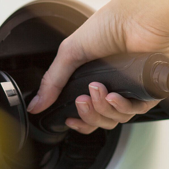 Eine Hand, die ein Ladekabel in den Anschluss eines Elektroautos anschließt