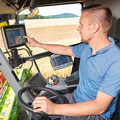 Ein Mann fährt einen Traktor, während ein Computer auf dem Armaturenbrett platziert ist.