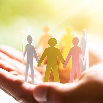 Hand mit ausgeschnittenen Papier-Menschen