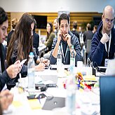 Teilnehmende sitzen an einem Tisch und arbeiten