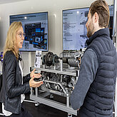 Jennifer Reinz-Zettler von der Bayern Innovativ GmbH im Austausch mit einem Teilnehmer an einem Ausstellungsstand.