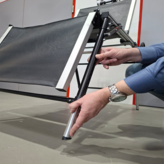 Hände stellen die Höhe eines Stuhlbeins mit schwarzem Bezug und silbernem Metallrohr ein