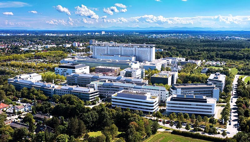 Eine Luftaufnahme eines großen, modernen Krankenhauskomplexes, umgeben von Grünflächen und Bäumen.