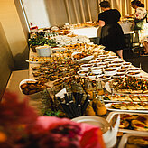 Ein Buffet mit einer Auswahl an Fingerfood, Snacks und Getränken steht für die Gäste bereit.