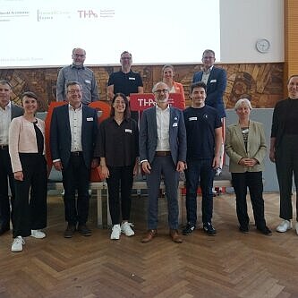 Team steht zusammen vor Leinwand