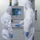 wei Fachleute in Schutzkleidung analysieren Daten an einem Computer.