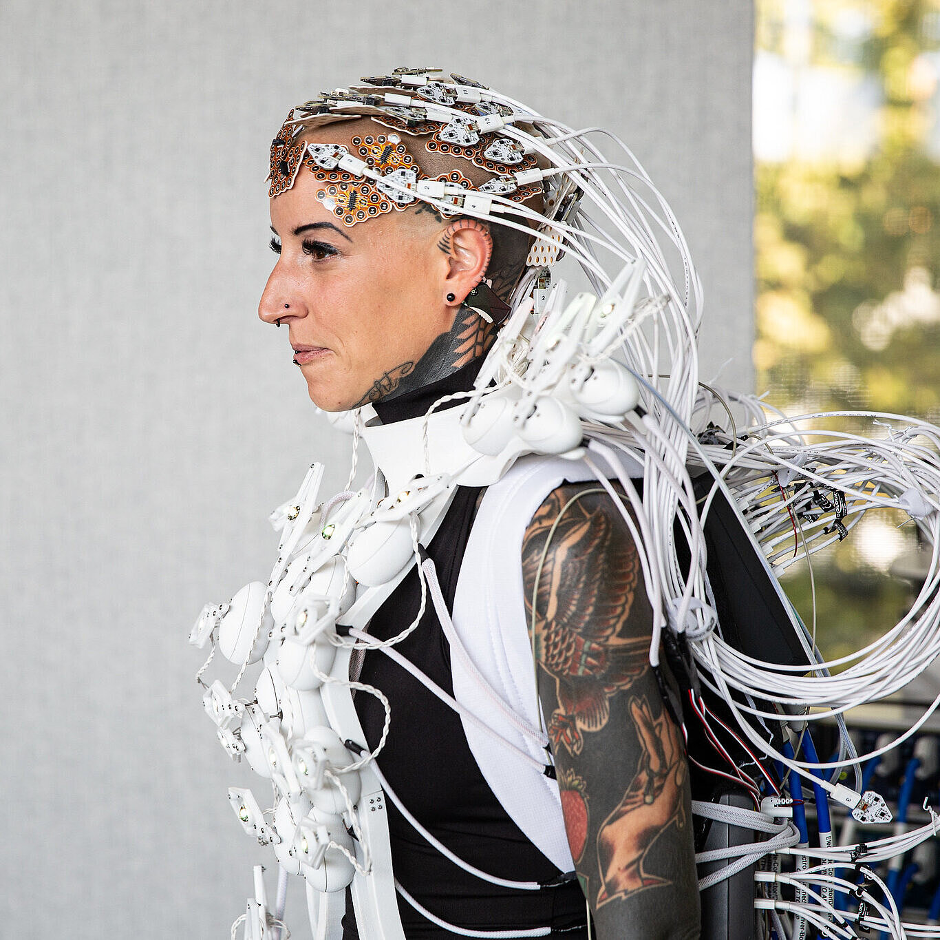 Person mit Headset aus Sensoren und Kabeln, das Kopf und Schultern umgibt.