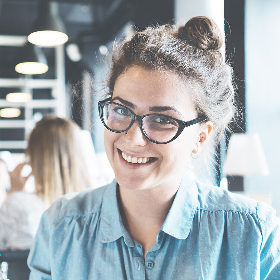 Porträt einer Studentin, die in einer Bibliothek sitzt